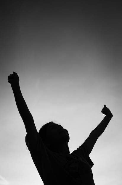 Silhouette de personnes les mains vers le haut.