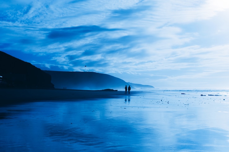 Photo silhouette de personnes marchant le long de la plage près de l&#39;océan