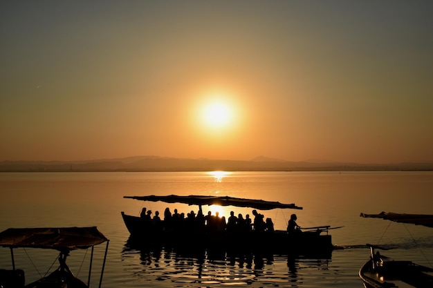 Photo silhouette de personnes sur la mer contre le ciel au coucher du soleil