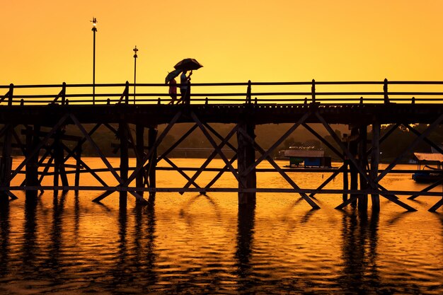 Photo silhouette de personnes sur un pont en bois contre le ciel au coucher du soleil