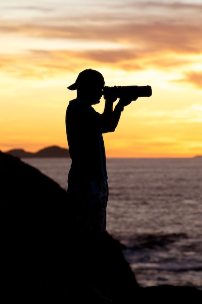 Silhouette d'un photographe avec un beau lever de soleil en arrière-plan sur la plage de Leblon à Rio de Janeiro