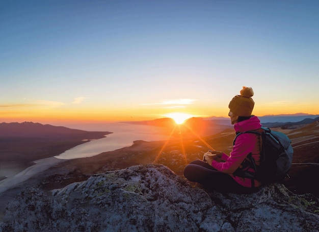 Silhouette d'un photographe qui filme un coucher de soleil sur les montagnes