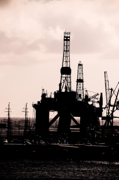 Photo silhouette de plate-forme de forage pétrolier sur un ciel nuageux