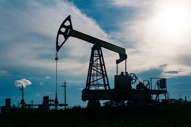 Silhouette d'un pumpjack avec pompe à piston sur un puits de pétrole sur fond de ciel