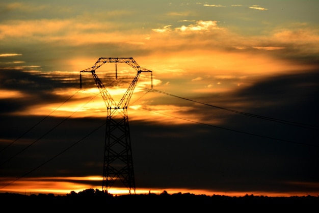 Silhouette d'un pylône électrique contre le ciel au coucher du soleil