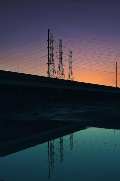 Silhouette de pylônes électriques contre le ciel au coucher du soleil