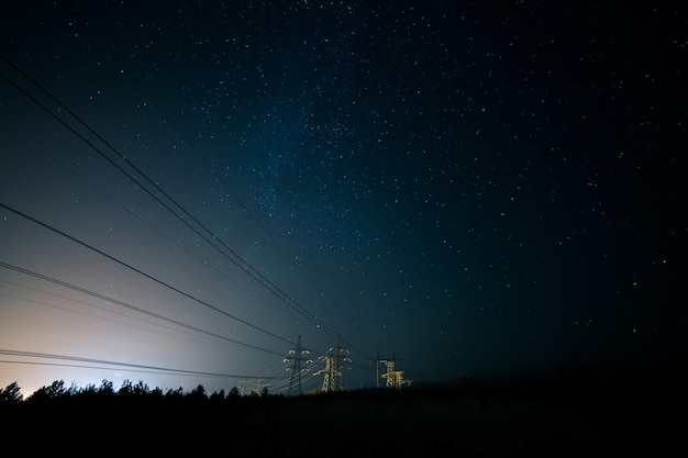 Silhouette de pylônes électriques contre le ciel la nuit
