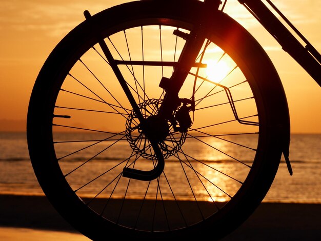 La silhouette d'une roue de vélo contre le ciel orange