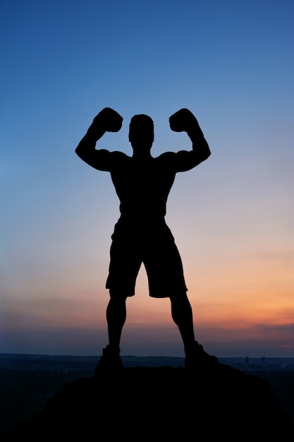 Silhouette sombre d&#39;un boxeur masculin musclé posant sur coucher de soleil