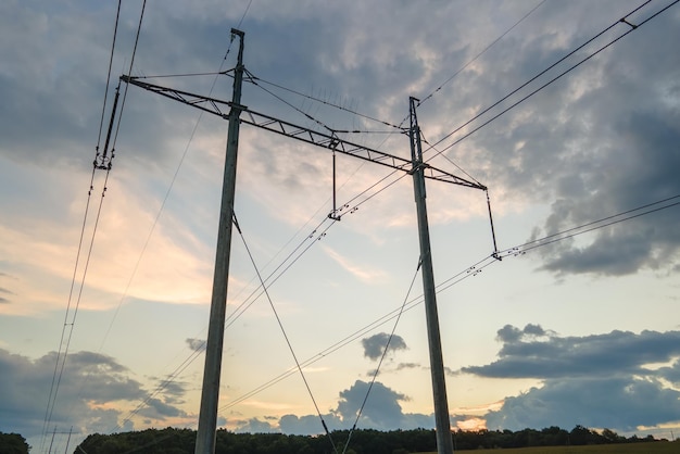 Silhouette sombre de la tour haute tension avec des lignes électriques au lever du soleil.