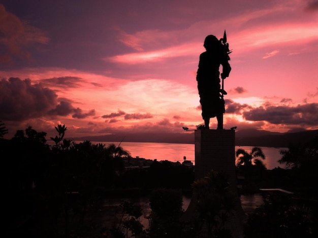 Photo silhouette de la statue sur un ciel nuageux au coucher du soleil