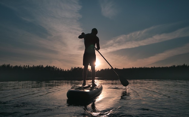 Photo silhouette de surfeur sup loisirs actifs sur l'eau