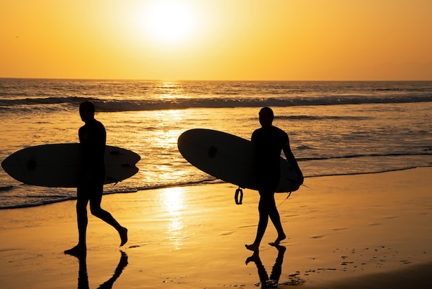 Silhouette de surfeurs portant leur planche de surf sur Sunset Beach