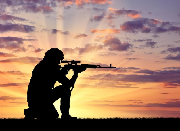 Silhouette d'un terroriste avec une arme sur fond de coucher de soleil