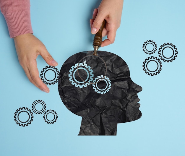 Silhouette d'une tête humaine et d'une main de femme avec une loupe Concept de santé mentale
