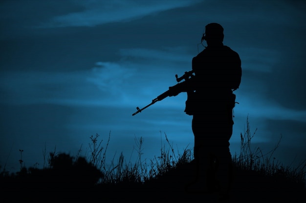 Silhouette de tireur d'élite militaire avec des armes la nuit