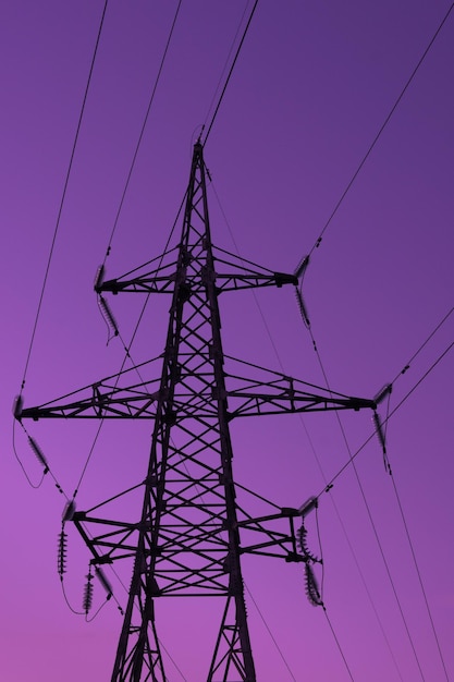 Silhouette de tour électrique haute tension sur fond violet clair