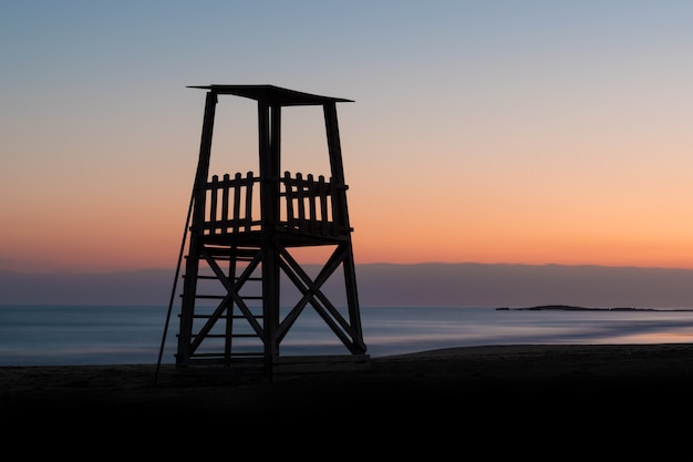 Une silhouette de tour de sauveteur contre un ciel de coucher du soleil