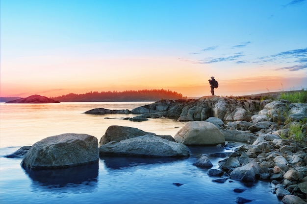 Photo silhouette de touriste avec appareil photo sur les rochers de l'île mystérieuse