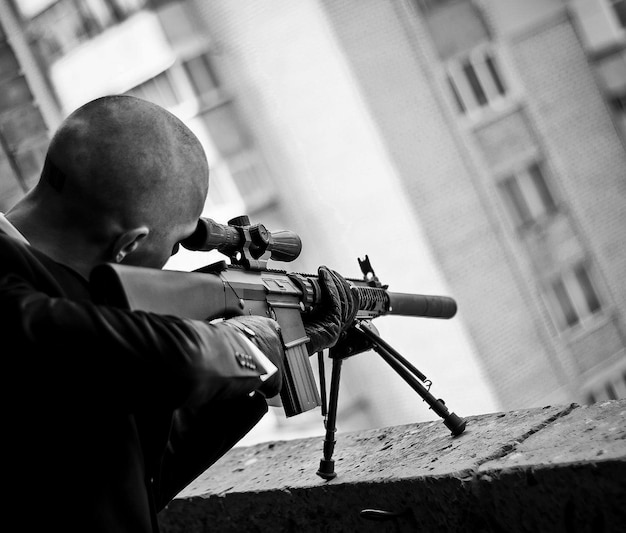 Silhouette d'un tueur en costume ou d'un tueur avec une arme à feu par jour. Fusil de sniper. photographie en noir et blanc