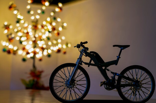 Silhouette de vélo miniature et arbre de Noël flou en arrière-plan.