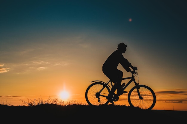 Silhouette d'un vététiste masculin au coucher du soleil dans les montagnes L'idée et le concept d'un mode de vie sain activités et sports de plein air