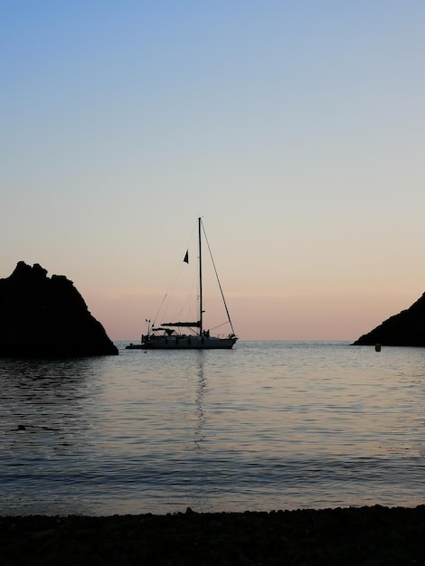 Photo silhouette d'un voilier en mer contre un ciel clair au coucher du soleil