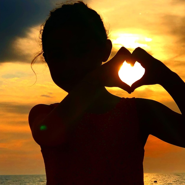 Photo des silhouettes d'amis sur la plage au coucher du soleil