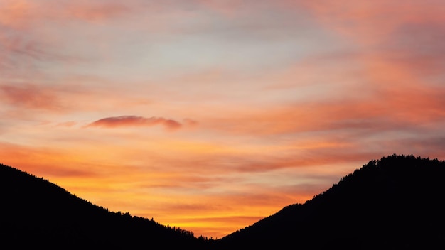 Silhouettes de collines avec forêt de conifères, fond de ciel coucher de soleil orange