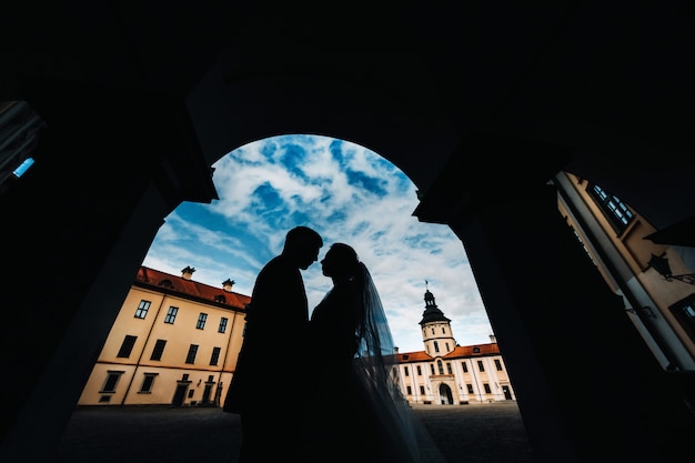 Silhouettes d'un couple amoureux au coucher du soleil sur le fond du château de Nesvizh