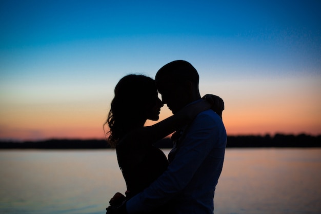 Photo silhouettes d'un couple amoureux de la romance au coucher du soleil.