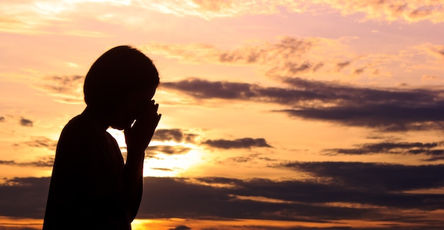 silhouettes femmes priant la main avec le fond de jeu de soleil.