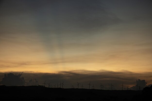 Silhouettes de ferme d'éoliennes sur les montagnes dans les zones rurales