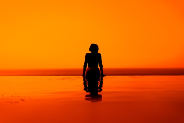 Silhouettes de filles sur la piscine au lever ou au coucher du soleil