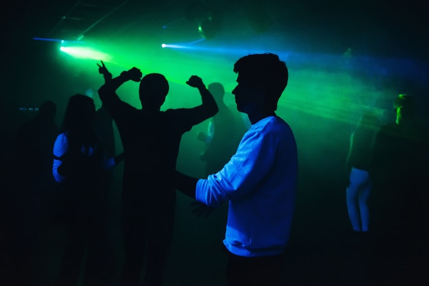 Silhouettes de gens qui dansent dans une discothèque sur la piste de danse à la fête