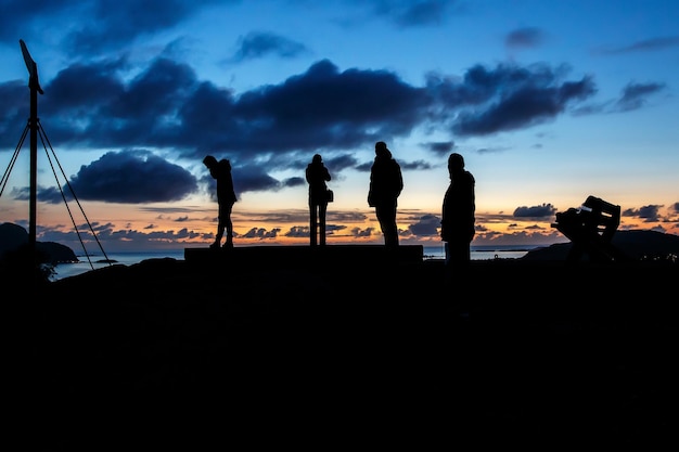 Silhouettes d'un groupe de personnes coucher de soleil et nuages sur le fond