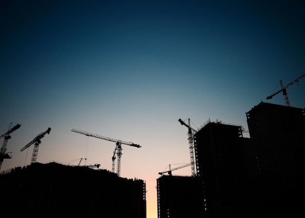 Silhouettes de grues de construction sur le coucher du soleil du chantier