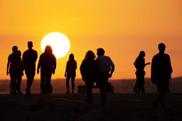 Silhouettes noires de personnes passant du temps sur la colline au coucher du soleil