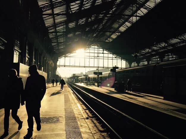 Des silhouettes de personnes attendant sur le quai de la gare.