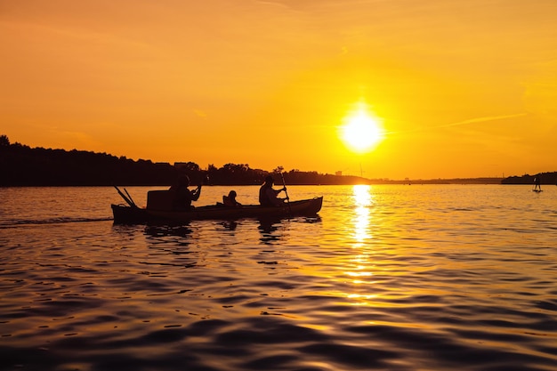 Silhouettes de personnes en bateau au coucher du soleil Famille de maman papa et enfant en bateau sur la rivière