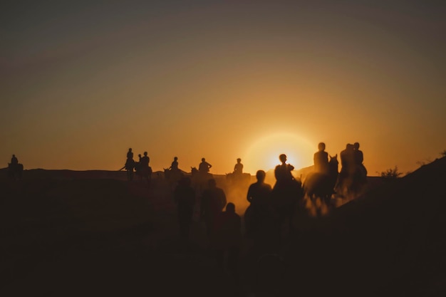Des silhouettes de personnes à cheval au coucher du soleil
