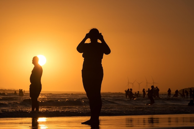 Silhouettes de personnes dans un coucher de soleil coloré sur la plage