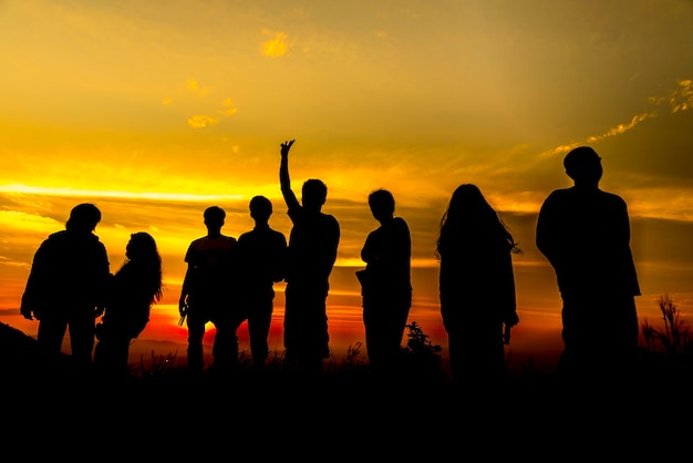 Des silhouettes de personnes debout sur la plage contre le ciel au coucher du soleil