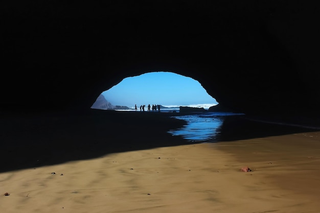 Silhouettes de personnes sur fond de falaises Afrique Maroc Legzira