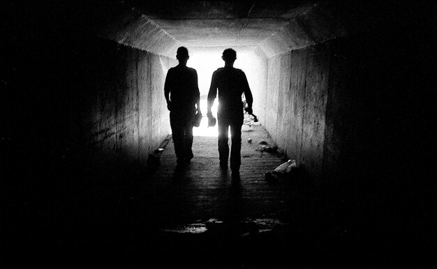 Photo des silhouettes de personnes marchant dans un tunnel éclairé