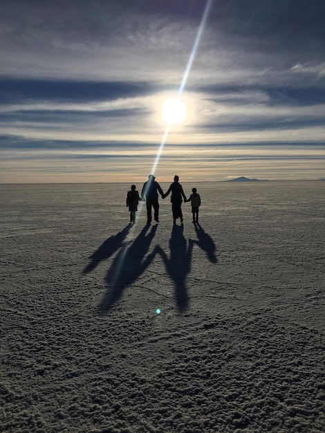 Photo des silhouettes de personnes sur la plage contre le ciel au coucher du soleil