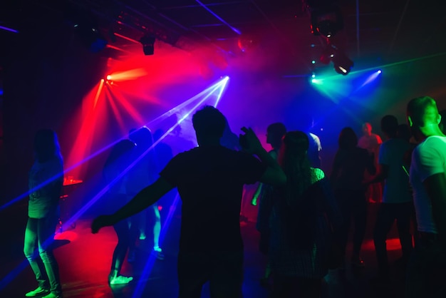 Silhouettes de personnes qui dansent en discothèque sur la piste de danse à la fête