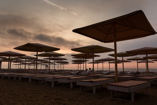 Silhuettes de transats et parasols sur une plage déserte le soir