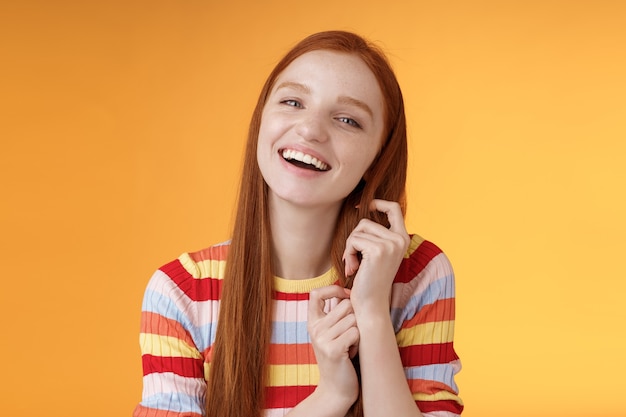 Silly beau séduisant jeune fille rousse vivante riant jouant coquette mèche de cheveux roux riant amusé blagues drôles de petit ami s'amusant génial date romantique, fond orange.