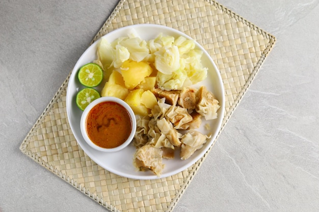 Siomay Bandung. Boulettes de gâteau de poisson avec pommes de terre et rouleau de chou servies avec des sauces aux arachides